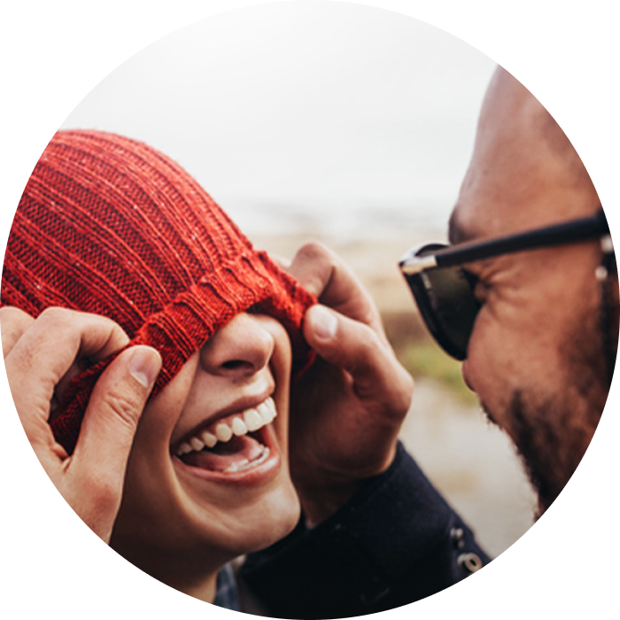 Woman laughing while having her eyes covered with a red hat.