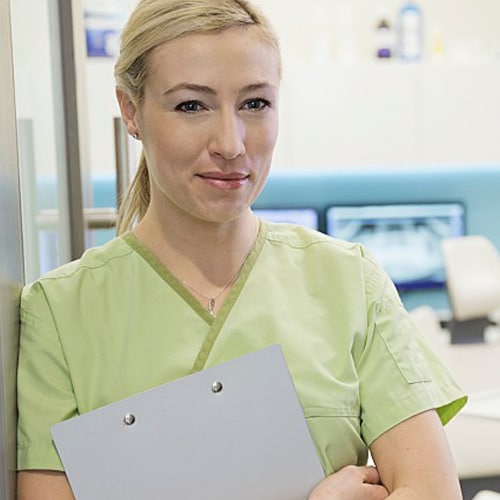 Nurse in green scrubs standing in treatment room doorway