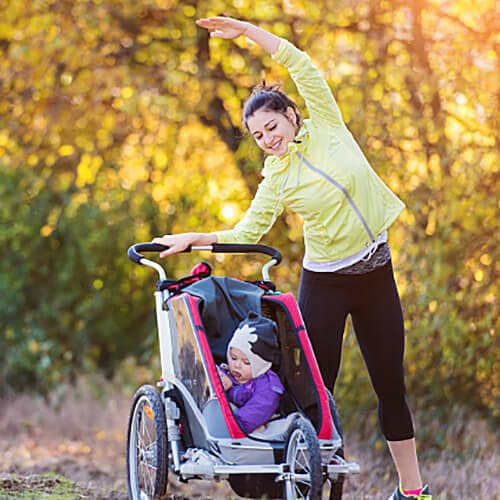 Women stretching besides her child's stroller outdoors