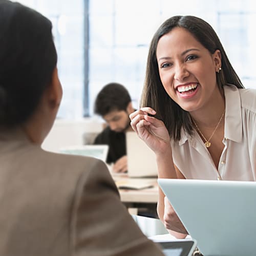 Three women smiling  while having a conversation