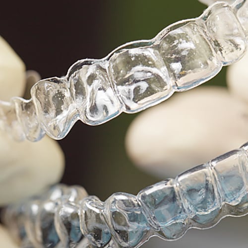 Person wearing white gloves holding teeth aligners
