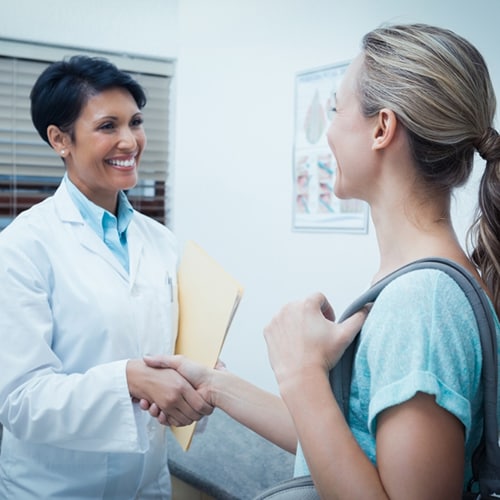 Doctor and nurse smiling at each other while shaking hands