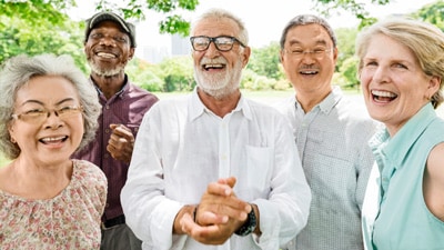 A group of five older people laughing outside 