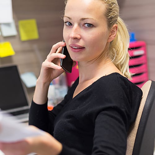 Woman talking on the phone while handing over paperwork