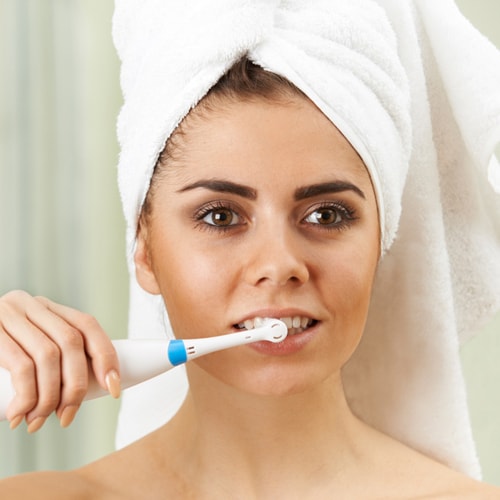 woman-brushing-teeth-electric-toothbrush-bathroom