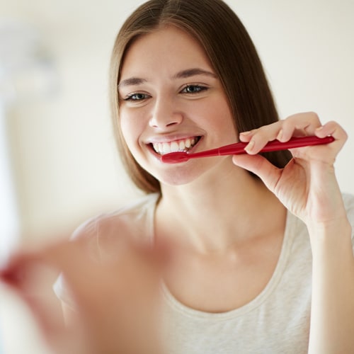 young-woman-brushing-her-teeth-mirror