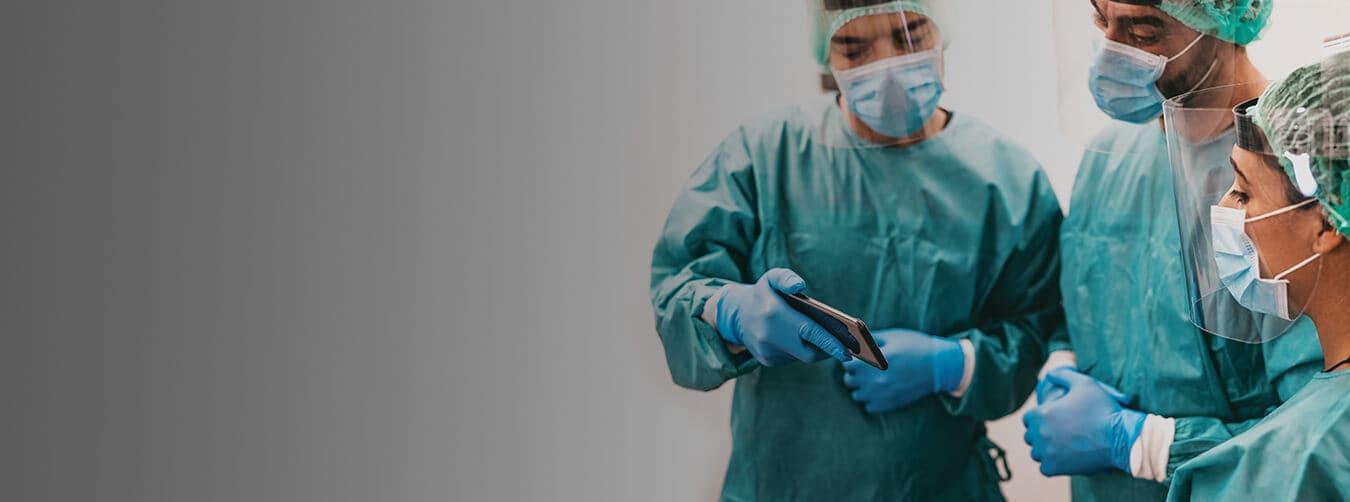 Man in a teal PPE suit with a face mask, face shield and gloves