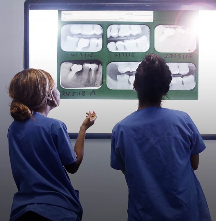 Two hygienist standing side by side looking at x-rays 