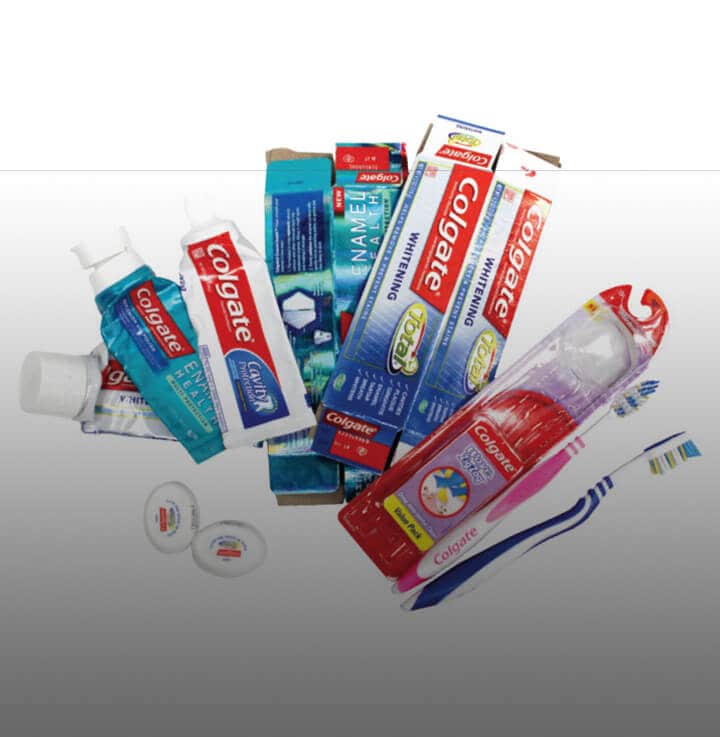 pile of recyclable Colgate product boxes, toothpaste tubes, and toothbrushes